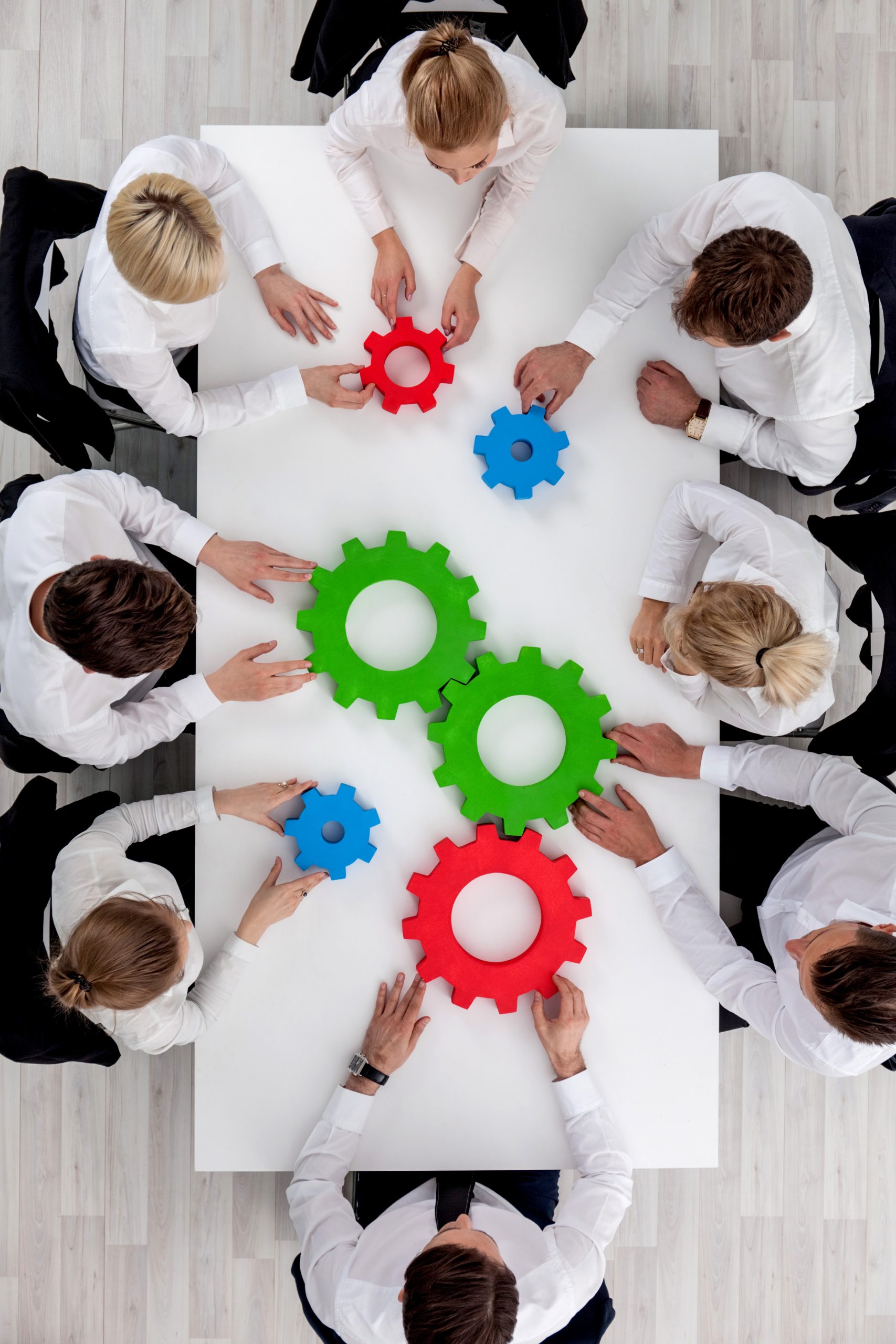 equipe-commerciale-assise-autour-de-la-table-avec-des-rouages-concept-de-travail-d-equipe